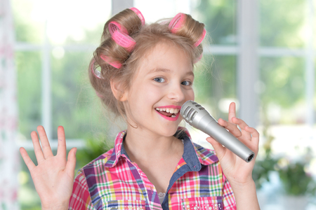 Portrait of adorable little girl singing karaokeの写真素材