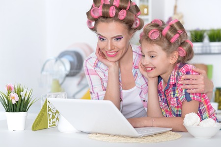 Portrait of beautiful young woman and little girl sitting at tableの写真素材