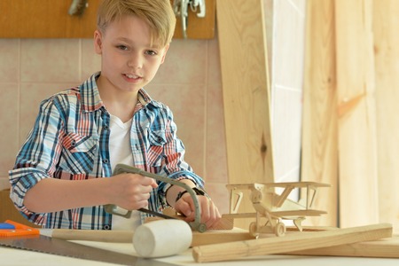 Cute little boy working with wood in workshopの写真素材
