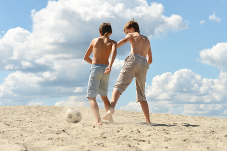Two brothers playing football against the skyの写真素材