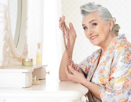 Portrait of happy senior woman sitting near dressing tableの写真素材