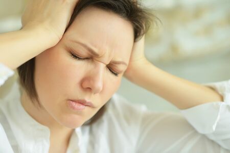 Portrait of young woman with headache posing at home