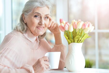 Close up portrait of beautiful smiling senior woman drinking teaの写真素材