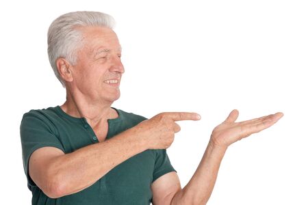 Senior man in green shirt pointing to the right on white backgroundの写真素材