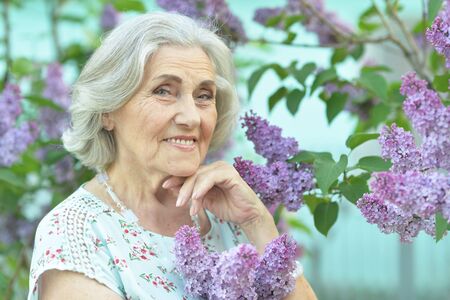 Portrait of happy senior beautiful woman on lilacs backgroundの写真素材