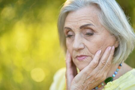 Portrait of sad senior beautiful woman posing in spring parkの写真素材