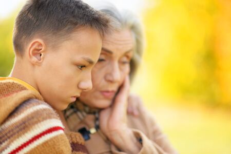 Portrait of grandmother and grandson hugging in parkの写真素材