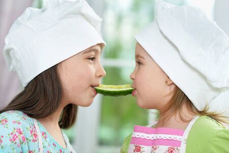Portrait of cute girls with cucumber in kitchenの写真素材