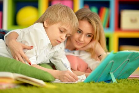 Mother with her son doing homework at homeの写真素材