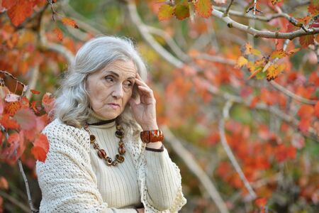 Portrait of sad senior woman in autumn parkの写真素材