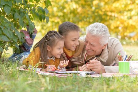 Portrait of children and grandfather doing homeworkの写真素材