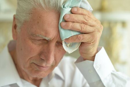 Portrait of senior man with headache at homeの写真素材