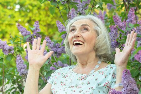 Portrait of happy senior beautiful woman on lilacs backgroundの写真素材