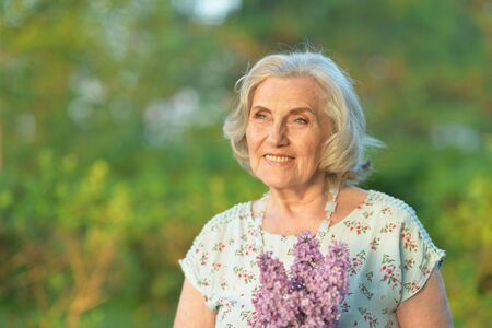 Portrait of happy senior beautiful woman with lilacs