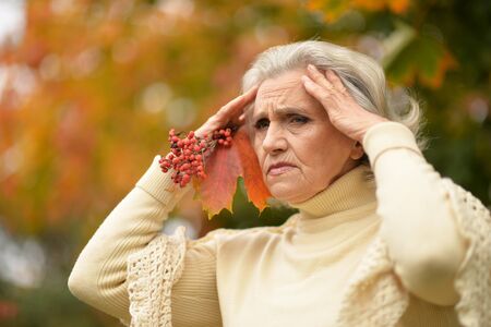 Portrait of sad senior woman in autumn parkの写真素材
