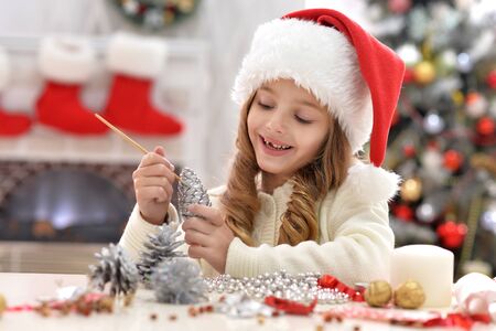Cute little girl in Santa hat preparing for Christmas at homeの写真素材