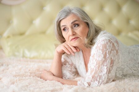 Portrait of thoughtful senior woman lying on bed