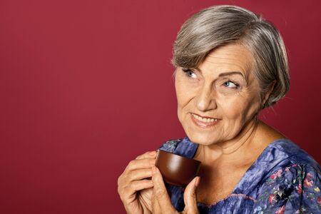 Close up portrait of beautiful smiling senior woman drinking teaの写真素材
