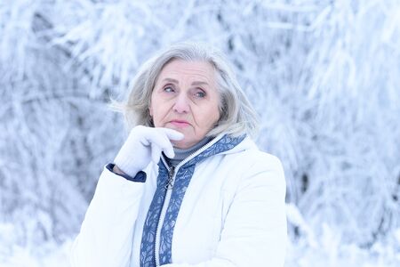 Portrait of sad beautiful senior woman posing in snowy winter park