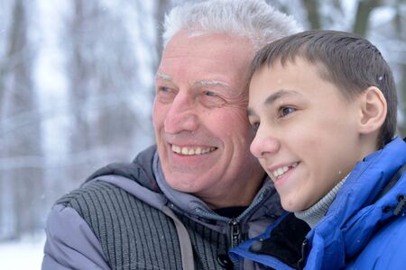 Smiling senior man and boy standing outdoors in winterの写真素材