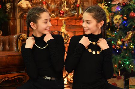 Cute little girls with necklaces near decorated Christmas treeの写真素材