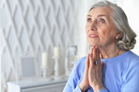 Portrait of senior woman praying at homeの写真素材