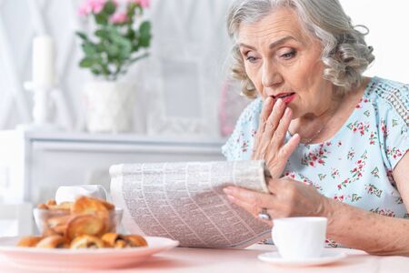 Portrait of thoughtful aged woman reading newspaperの写真素材