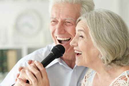 Close up portrait of senior couple singing karaokeの写真素材
