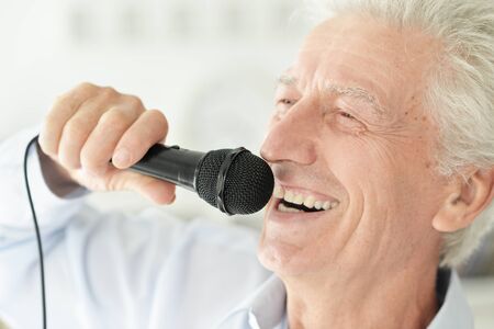 Close up portrait of senior man singing with microphoneの写真素材