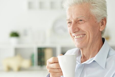 Portrait of smiling senior man drinking coffee at homeの写真素材