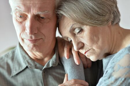 Portrait of sad senior couple posing at home