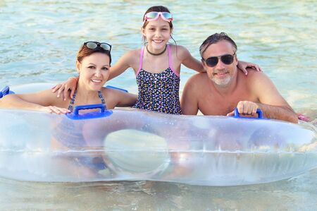 Happy Dad, mother and daughter relax in the pool