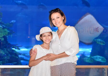 Portrait of happy mother with daughter posing aquarium