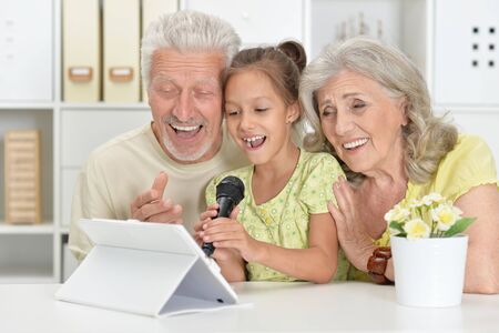 Portrait ofgrandparents with granddaughter singing karaokeの写真素材