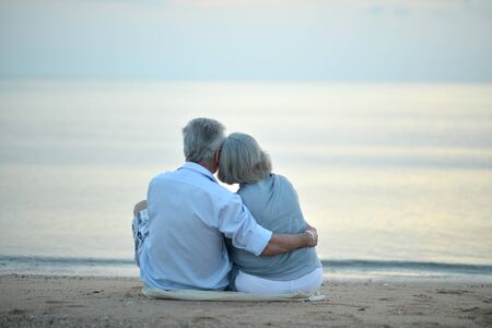 Happy elderly couple resting on tropical beachの写真素材