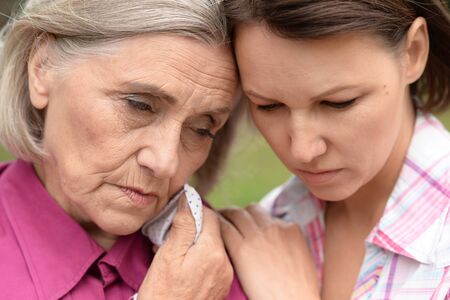 Close up portrait of sad senior woman with adult daughter