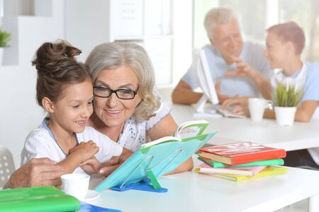 Grandmother with cute little girl doing homework together