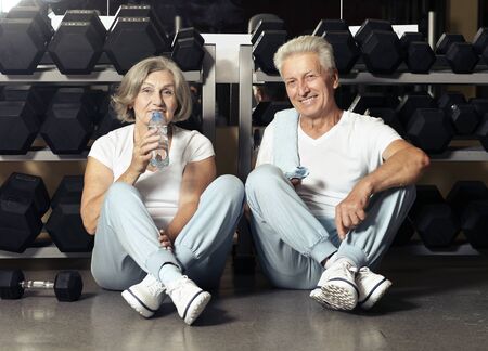 Portrait of senior couple drinking in gymの写真素材