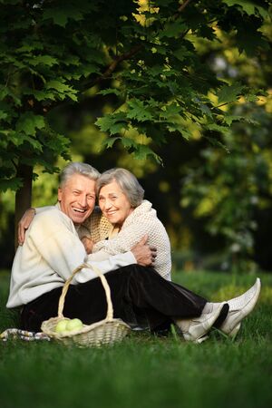 Portrait of beautiful senior couple sitting on grassの写真素材