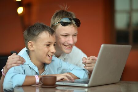 Portrait of happy young boys using laptop computerの写真素材
