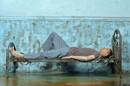 Portrait of man on the metal rusty bed in prisonの写真素材