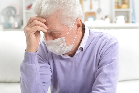 Portrait of sad sick senior man with facial mask