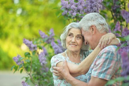 Beautiful senior couple hugging on a lilac background in the parkの写真素材
