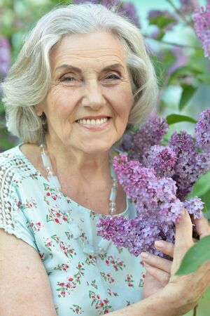 Happy senior beautiful woman on lilacs backgroundの写真素材