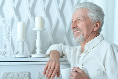 Portrait of smiling senior man drinking tea at homeの写真素材