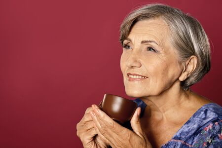 Portrait of beautiful smiling senior woman drinking teaの写真素材
