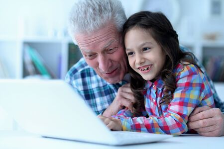 Emotional senior man with granddaughter using laptop singing karaoke