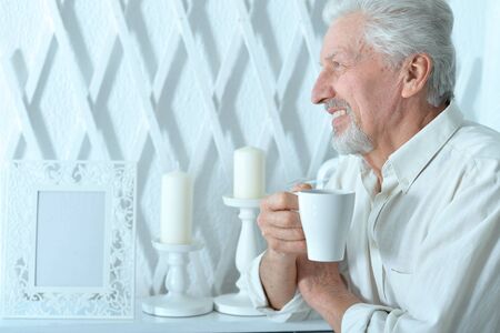 Smiling senior man drinking tea at homeの写真素材