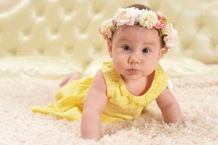 Cute little baby girl in wreath on bed