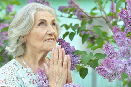Close-up portrait of senior beautiful smiling woman prayingの写真素材